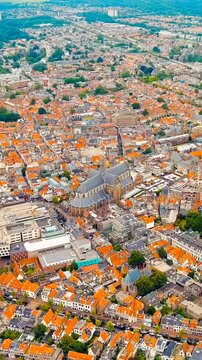Vertical video. Haarlem, Netherlands. Grote Kerk rising above dense terracotta rooftops, panoramic Drone footage over the Spaarne river and historic city center under overcast summer skies. Drone foo