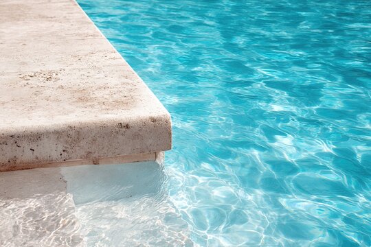 Shining turquoise swimming pool water ripples near travertine stone border with underwater steps. Suitable for premium outdoor hardscaping material brochure, luxury spa catalog or travel agency banner