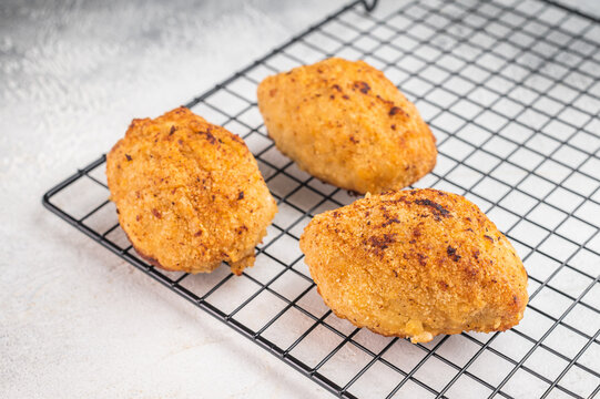 Chicken Kiev butter chicken cutlet stuffed chicken with herb butter filling on wire rack with fork on light background