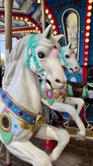 Closeup of ornate white carousel horses with colorful decorations at a traditional amusement park ride © Olshanetskaia