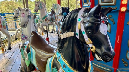 Black and white carousel horses with colorful decorations on a traditional amusement park ride outdoors © Olshanetskaia
