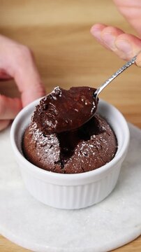 Spoon shows melted center of molten cake to camera. Molten cake helps pastry students learn timing and liquid center. Molten cake lesson in pastry school explains soft texture and flowing chocolate.
