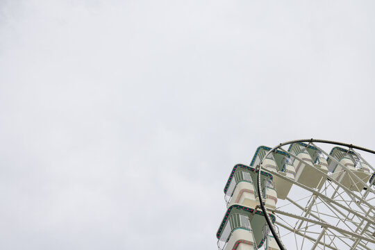 Traditional Ferris wheel at Llandudno in North Wales viewed from a low angle with white framework passenger gondolas and small coloured lights rising into a pale cloudy coastal sky