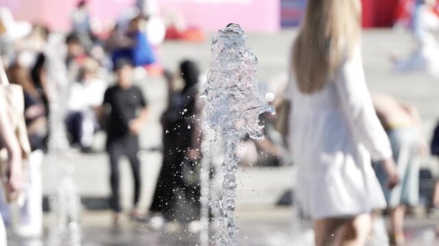 People enjoying a refreshing fountain spray in a city park on a hot summer day