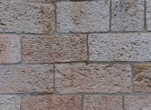 Texture of an authentic light beige Jerusalem stone wall with a rough, uneven surface