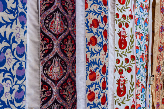 Close up of traditional middle eastern fabrics featuring colorful embroidered pomegranate and floral patterns