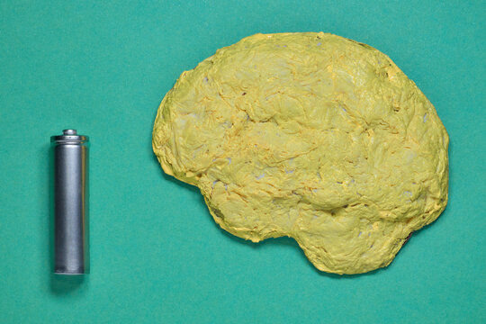 Concept of mental energy and exhaustion, featuring a yellow brain and a battery against a green background.