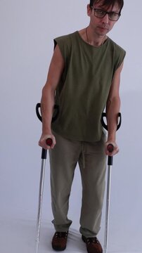 homem paciente em recupera&ccedil;&atilde;o andando com apoio de muletas 