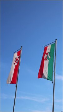 Waving flags from dusseldorf and northrhine westphalia on blue sky background show european and german represented by dusseldorf flag and northrhine westphalia flag as vertical video both flags as set