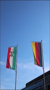 Waving flags from Germany and northrhine westphalia on blue sky background show european and german represented by German flag and northrhine westphalia flag as vertical video both flags as set