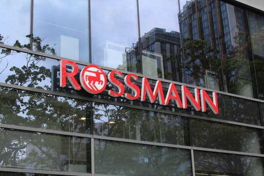 Warsaw, Poland, May 15, 2026. Modern exterior storefront sign of Rossmann drugstore on a glass modern urban building facade reflecting surrounding cityscape. High quality photograph