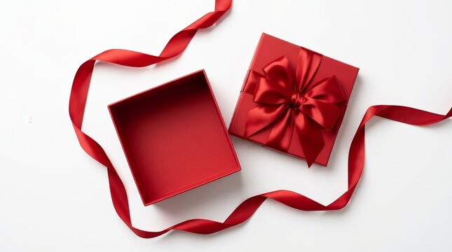Open red gift box with satin ribbon bow on white background in top view flat lay.