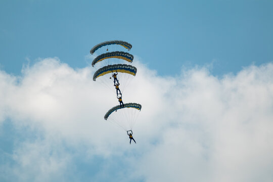 Scenic parachutists formation airshow with yellow-blue ukrainian parachutes above clouds
