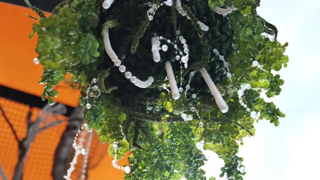 Artificial hanging plant decoration with white beads and pearls against orange and blue