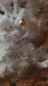Vertical video. Female hands decorating white Christmas tree with Christmas decoration in cozy home.