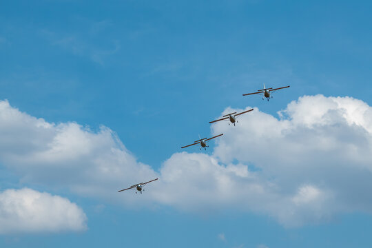 Small ultralight planes soar in close formation across a clear sky, skilled group flying at an airshow