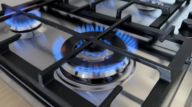 Close up view of a modern gas stove burner surface, showing metal grate details and clean cooktop elements, perfect for kitchen appliance articles, cooking blogs, or home decor content