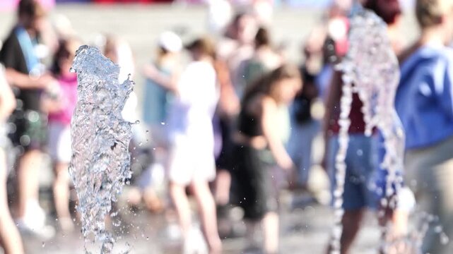 Water jets rising from a fountain cooling people on a hot summer day