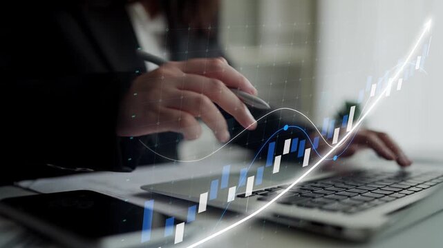 A business professional focuses on a laptop while analyzing financial data represented by an overlay graph, showcasing growth trends in a modern workspace. Copula