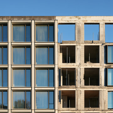 Half finished building facade with glazed windows beside bare concrete frame