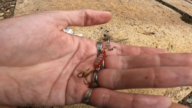 Close up of fisherman hand holding red spinner bait lure for spin fishing. Fishing tackle and equipment concept.