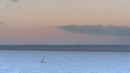 Minimalist winter landscape with yellow navigation buoy in frozen sea at sunset  Baltic Sea © Thomas Trapani