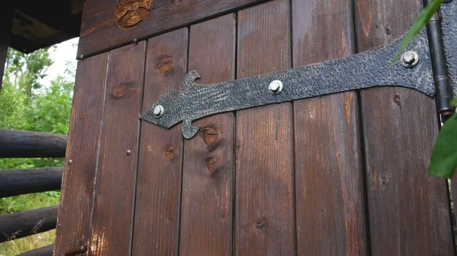 Slightly opened antique wooden door with decorative wrought iron hinges and hardware. Authentic architectural detail, historic craftsmanship, traditional design, and old-world heritage concept.