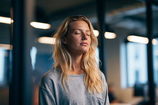 Young Woman Meditating and Relaxing in Modern Office