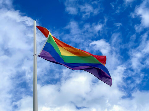 rainbow pride flag on pole and blue sky