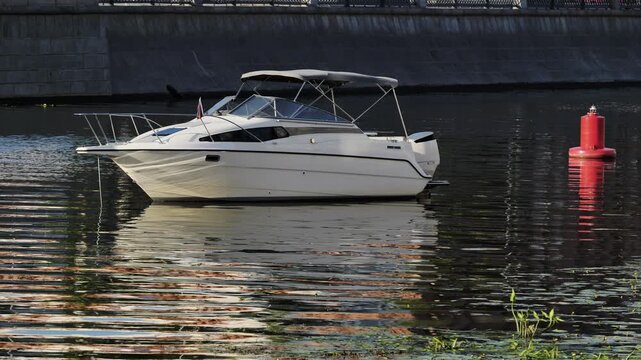 White motorboat cruising on a river with a red navigational buoy and ripples