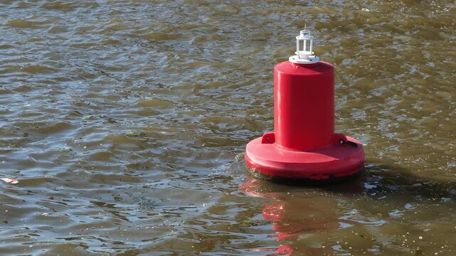 Red navigational buoy floating in wavy river water marking a waterway channel