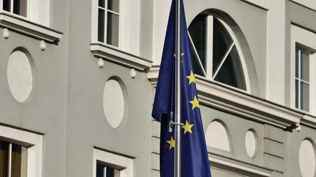 European Union flag flying on a flagpole against a building, representing international cooperation