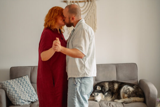 Couple kissing while slow dancing in a living room