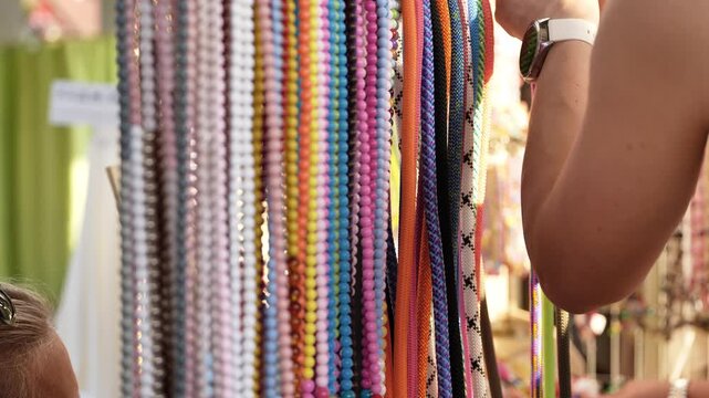 Woman shopping for colorful handmade beaded necklaces and ropes at a market stall