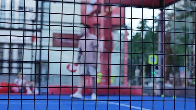 Padel players enjoying a competitive game on a blue court behind a wire fence