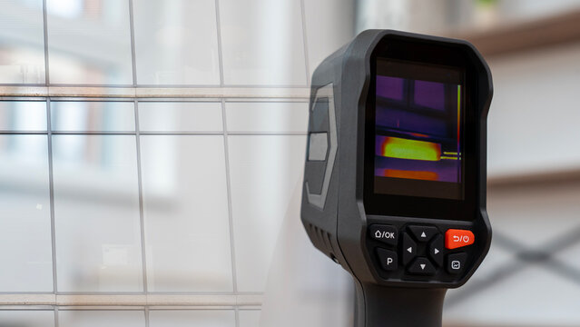 Thermal camera displays temperature readings with color gradients. Black device has red 'ON' and black 'OFF' buttons. White grid window is softly blurred in the background