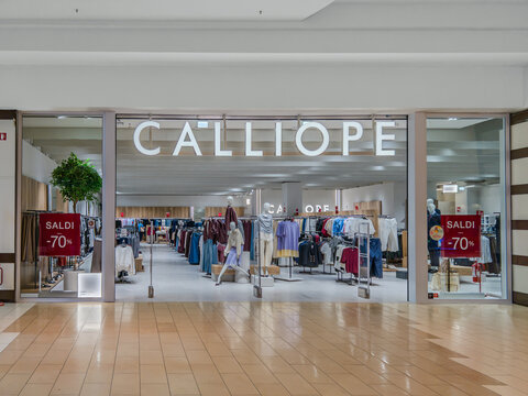 Italy - August 28, 2026: Calliope fashion clothing boutique located inside  bright shopping mall. The retail shop entrance features a large illuminated brand logo sign and red promotional banners 