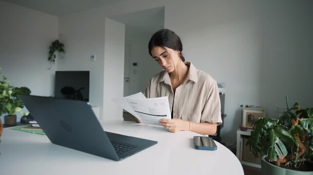 Stressed woman reviewing bills and financial documents at home