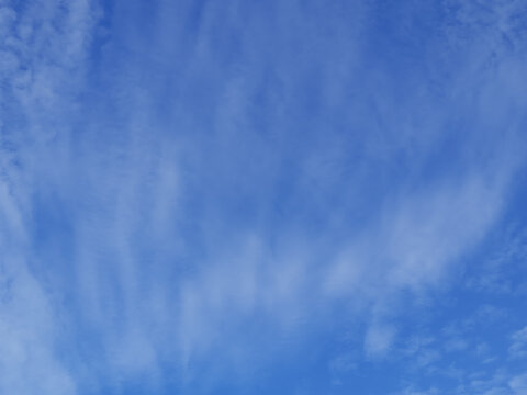 Blue sky background with vertical white cirrus clouds and wispy feathery texture