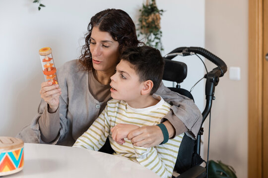 Mother assisting child with cerebral palsy during sensory activity