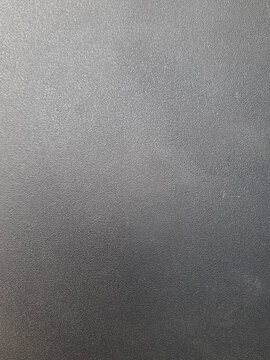 Black textured plastic surface with fine matte grainy finish for background graphic overlay and synthetic material backdrop