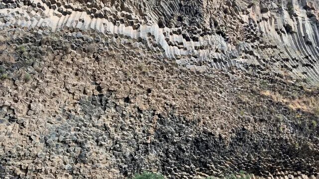 Garni, Armenia - August 26, 2026: Unique basalt column formations create intricate patterns on a rocky cliffside in a beautiful natural landscape