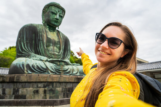 Turista mujer  disfrutando su visita por Jap&oacute;n, tomandose una selfie en el gran buda de  kanagawa.