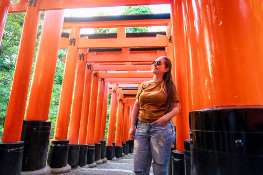 Turista mujer disfrutando su visita en Kioto, Japon, contemplando las puertas torii del santuario Fushimi Inari-taisha