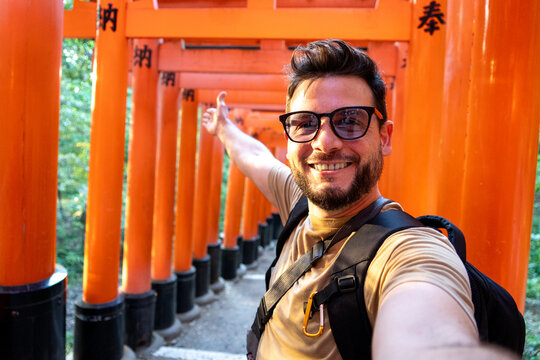 Turista disfrutando su visita en Kioto, Japon, tomandose una selfie en las puertas torii del santuario Fushimi Inari-taisha