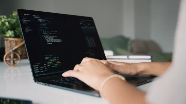 Female software engineer typing code on laptop