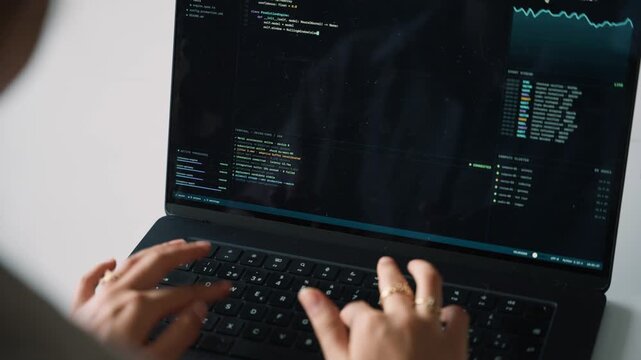 Female software engineer writing programming code on a laptop
