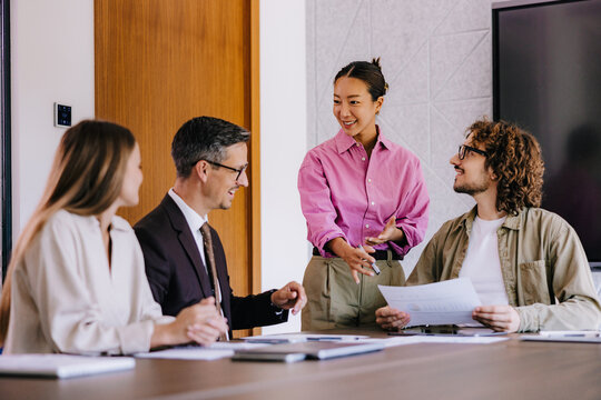 Smiling Team Discussing Reports in Office Meeting &mdash; Collaborative Business Presentation and Strategy Session