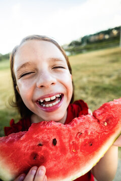 Happy child girl eating watermelon fresh fruit at park city - Summer vacation concept - Vertical photo