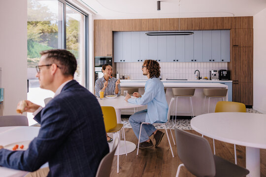 Coworkers Chatting Over Coffee in a Modern Office Kitchen During a Casual Break